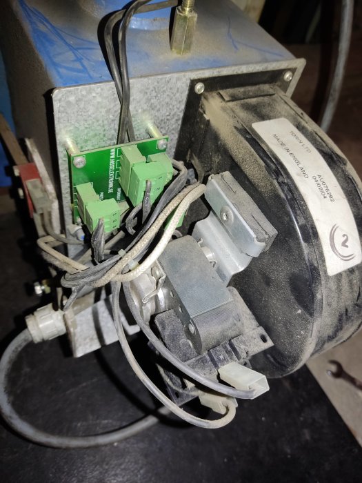 Närstående bild av en smutsig elektrisk motor med kabelanslutningar och en etikett som visar tillverkaren.