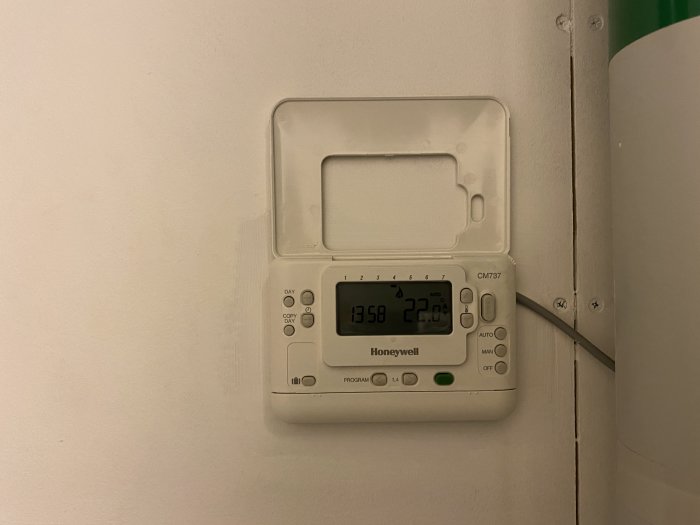 Honeywell termostat på vägg visar 22 grader i ett hem med problem med uppvärmning på övervåningen.