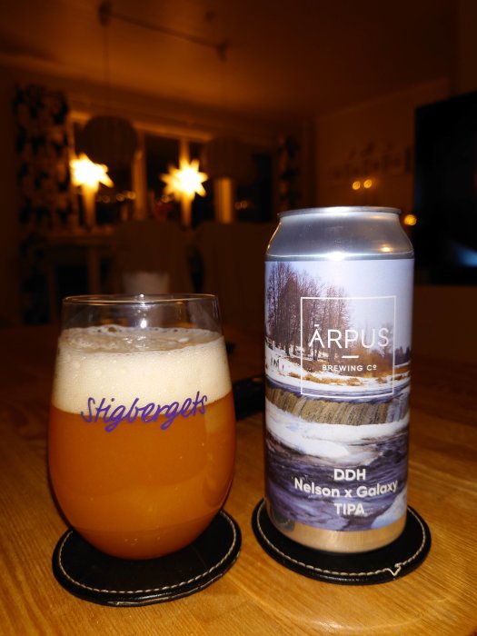 Ölglas märkt Stigbergets fyllt med öl bredvid en burk från Arpus Brewing Co. på ett bord.