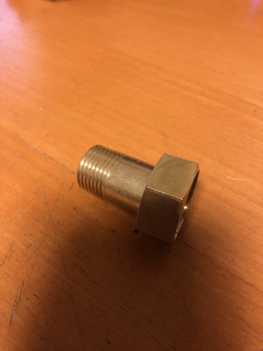 Gängad koppling för cirkulationspump, 3/4 tum, mot träbakgrund.