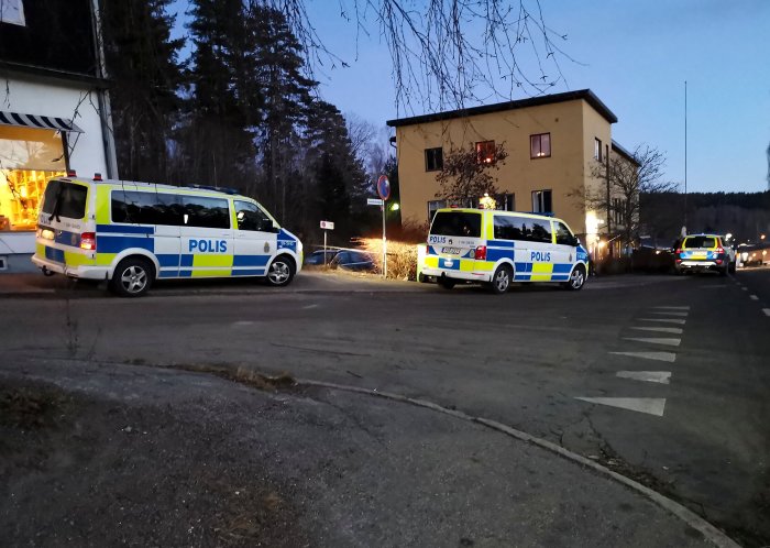 Polisfordon parkerade vid en korsning under skymningen, möjlig razzia.