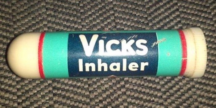 Vicks inhalator liggande på ett brungrått tygunderlag.