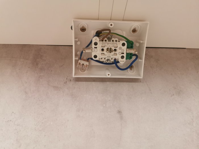 Eluttag öppnad med synliga WAGO-kopplingar och elektriska ledningar på betongvägg.