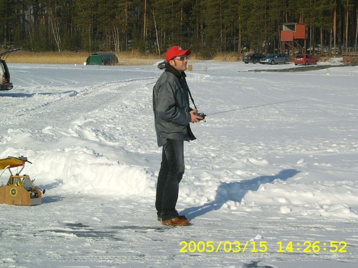 Person som håller en fjärrkontroll med teleskopantenn på ett snötäckt fält.