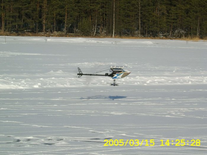 Radiostyrd helikopter med teleskopantenn och metanolmotor på snötäckt mark.