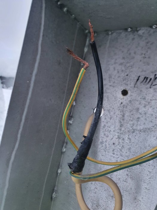Skadad elektrisk kabel med exponerade koppartrådar och isoleringstejp