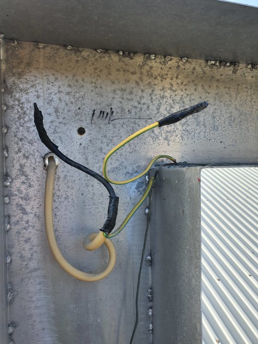 Elkablar med isoleringsskador fasttejpade mot en metallkonstruktion.