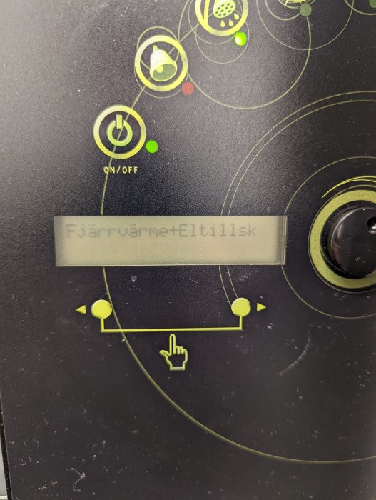 Värmesystemets kontrollpanel med displayen visande 'Fjärrvärme+Eltillsk' samt ON/OFF-switch.