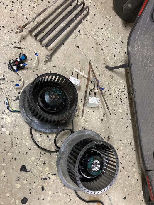 Värmeelement, två motorer och givare upplagda på ett verkstadsgolv.