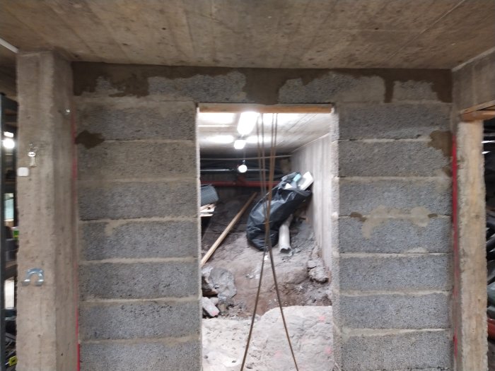 Vägg med murad spännform och armeringsjärn i byggprojekt, förberedd för gjutning.