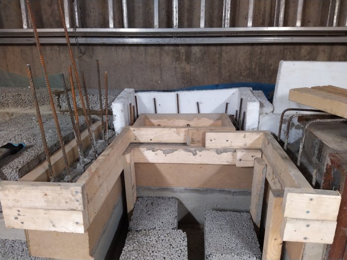 Spännform med armeringsjärn och träställningar förberedda för gjutning i ett pågående byggprojekt.