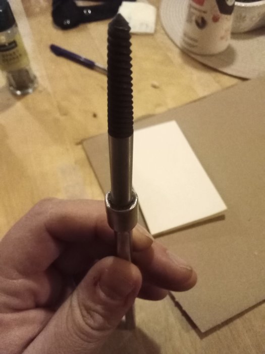 Hållen hand med sammansatt verktyg bestående av en grispitt och förlängare mot en suddig bakgrund.