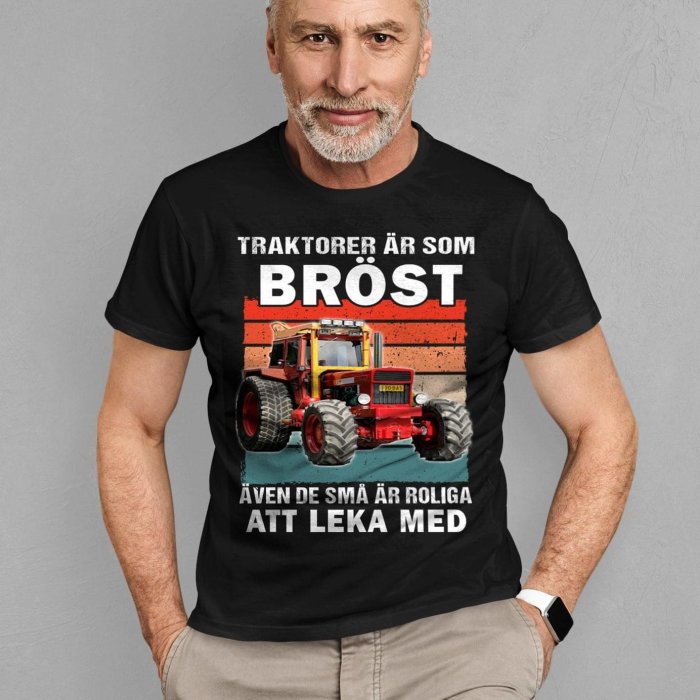 Man i svart t-shirt med tryck: traktor och text "Traktorer är som bröst, även de små är roliga att leka med".