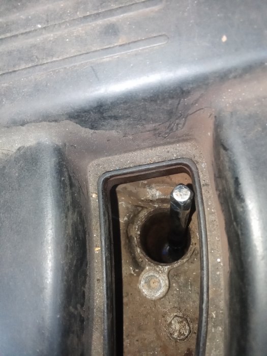 Närbild av en smutsig bilbatterihållare med korrosion runt hållfästen och pol.