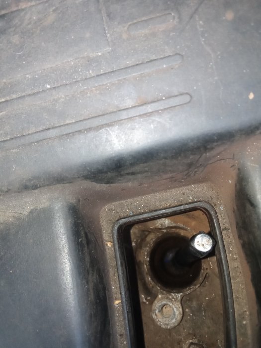 Närbild på en smutsig motoroljepåfyllningsöppning på en bil.