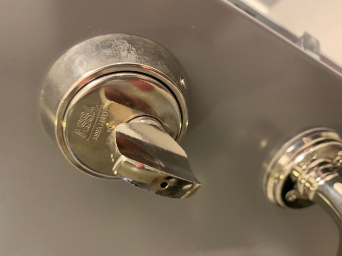 ASSA 13S vredcylinder fastmonterad i dörr, användare försöker demontera för byte till digitalt lås.
