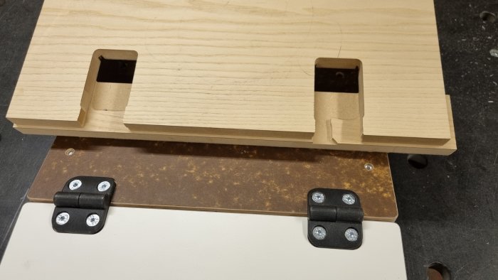 Hantverksjigg med glappfria gångjärn och infästa komponenter på en arbetsyta av trä och metall.