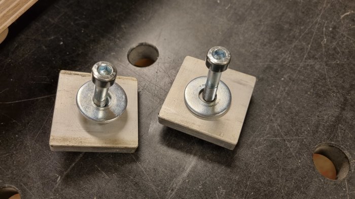 Två egengjorda monster t-nuts för fäste på svarv, med bultar och brickor på träblock.