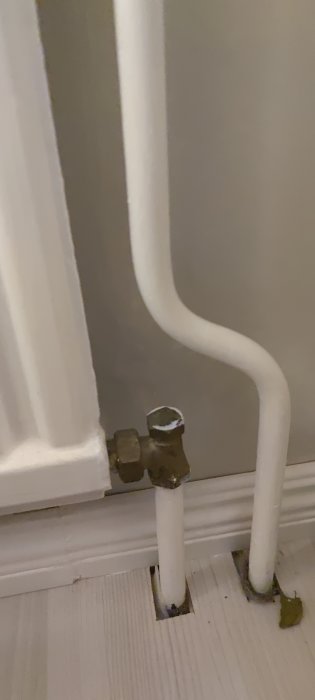 Radiator med termostat och anslutande rör på bottenvåningen, rören är ljumma nära termostaten.