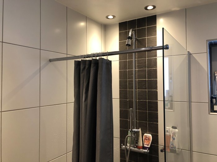 Badrum med kaklade väggar och duschstång, eventuell springa vid fästpunkt.