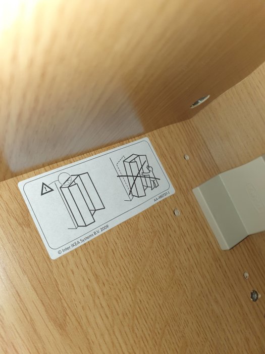 Inuti en Ikea-garderob med instruktionsetikett och synliga skruvhål i trähylsan.