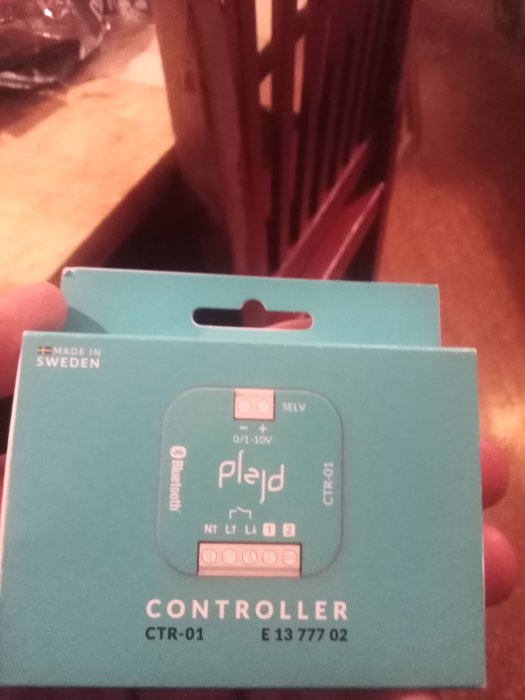 Hand håller en förpackning av Plejd Controller CTR-01, en enhet för smart belysningskontroll, med text "Made in Sweden".