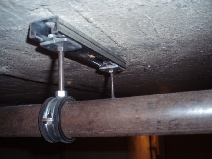 Installation av rör med Fischers skensystem fäst i betongtak.