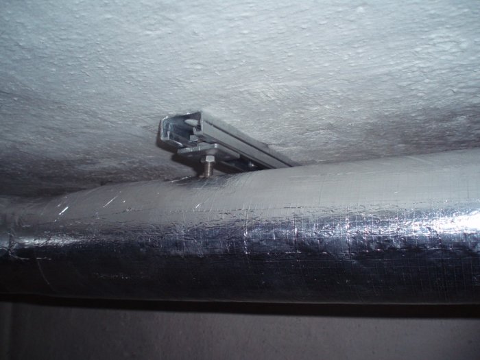 Installation av Fischers skensystem på isolerade rör under tak.