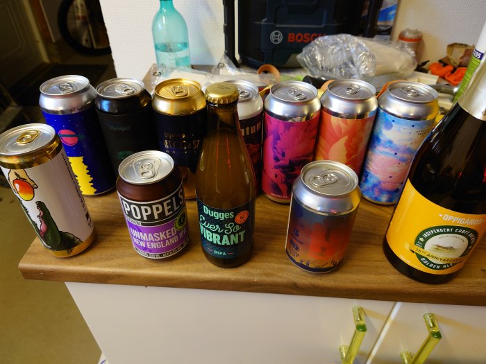 Samling av olika ölburkar och flaskor från Poppels, Dugges och andra mikrobryggerier på ett bord.