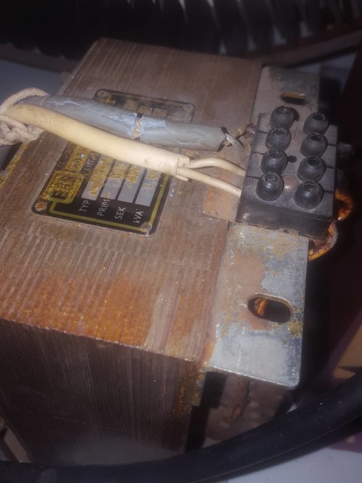 Gammal elektrisk klump med kopplingar och sliten isolering på kablar, tecken på korrosion och ålder.