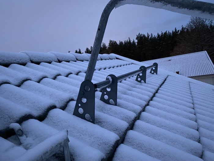 Säkerhetsräcke på snötäckt tak, potentiell hinder för solpanelsinstallation.