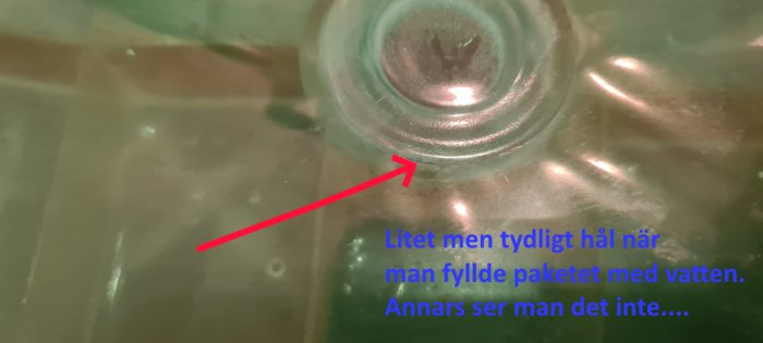 Närbild av vattenpaket med markerat litet hål där vatten strilar ut, illustrerande en läcka som upptäcktes under test.