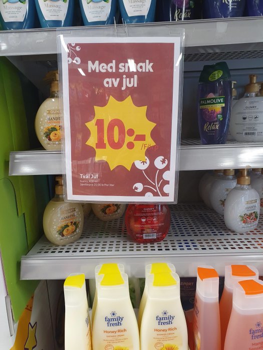 Reaskylt med texten "Med smak av jul 10:-" framför hyllor med diverse hygienprodukter som tvål och duschkräm.