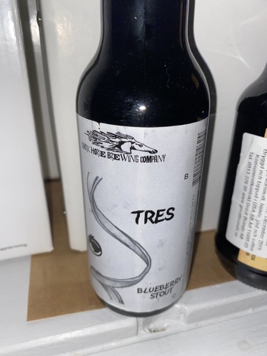 Flaska av "TRES Blueberry Stout" från Dark Horse Brewing Company på en hylla.