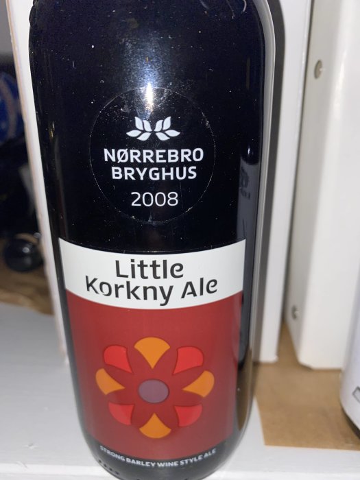 Flaska av Nørrebro Bryghus Little Korkny Ale från 2008 med röd etikett och blomlogotyp.