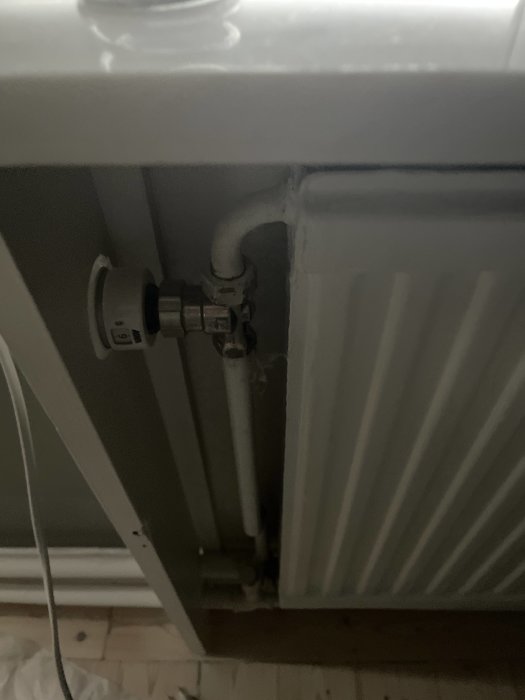 Radiator med termostat på maxinställning och synliga röranslutningar mot väggen.