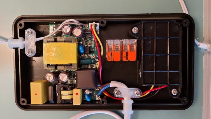 Öppen elektronikbox med kretskort, lödningar och WAGO 221 kopplingsklämmor i vägginstallation.