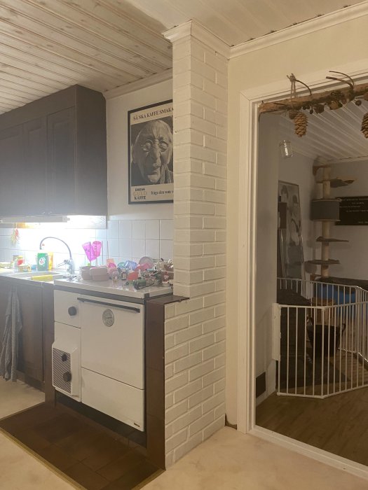 Kök med vitmurad vägg och vedspis, murat brandskydd intill och köksskåp ovanför, frågor om renovering ställs.