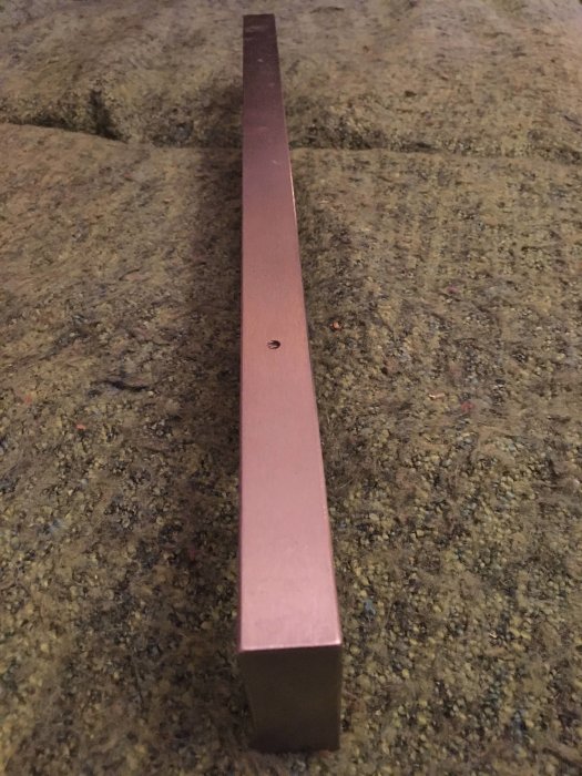 Metallprofil med urfräst långsida och skydd, liggande på granitbänk.