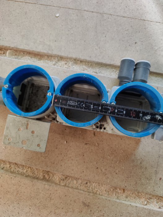 Mätning av CC-avståndet på 69mm mellan två eldosor med ett mätband.