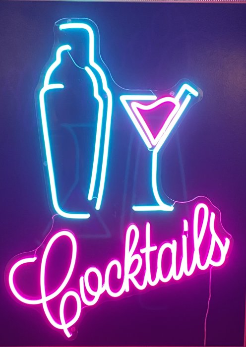 Neonskylt med kontur av en flaska och ett cocktailglas, texten "Cocktails" undertill i rosa.