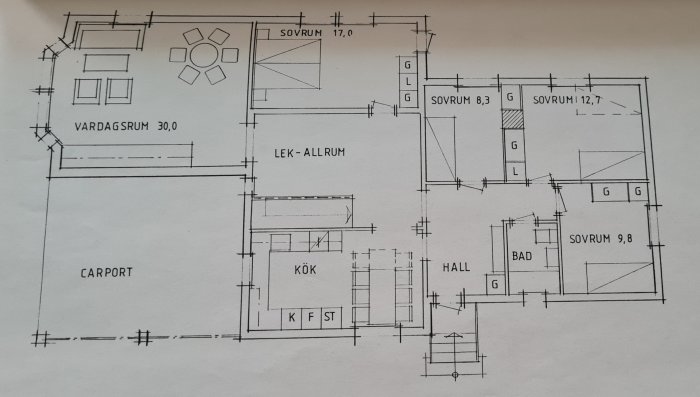 Arkitektritning av en husplan med vardagsrum, sovrum, kök, lek-allrum, och carport.