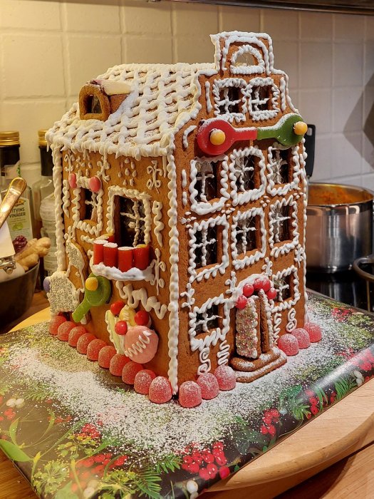 Pepparkakshus med tennisinspirerade detaljer på ett köksbord, dekorerat med glasyr och godis.