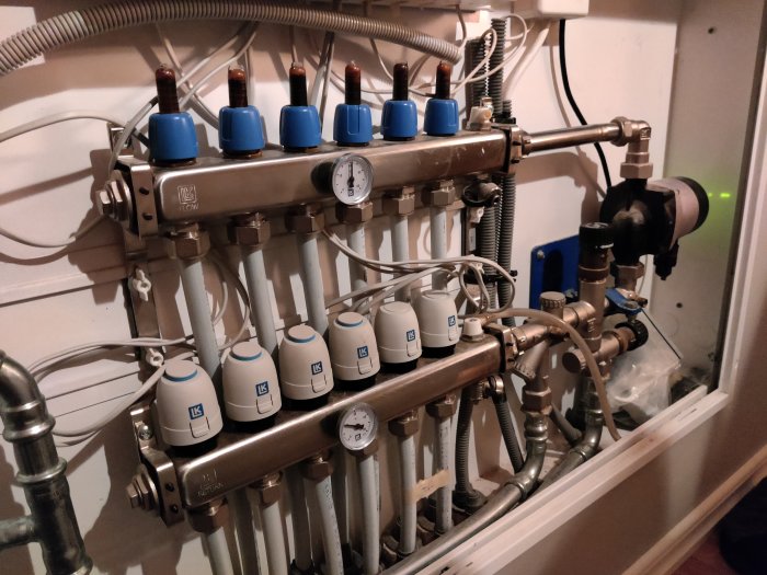 Värmesystem med fyra rumsregulatorer, sex ledningar och termometrar som visar temperaturer.