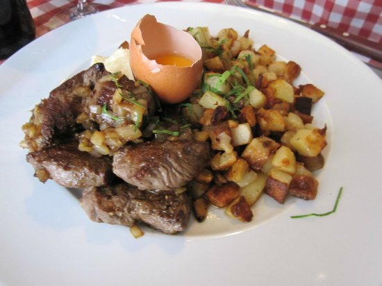 Biff Rydberg med kuber av stekt potatis, stekt lök och äggula i äggskal på en vit tallrik.