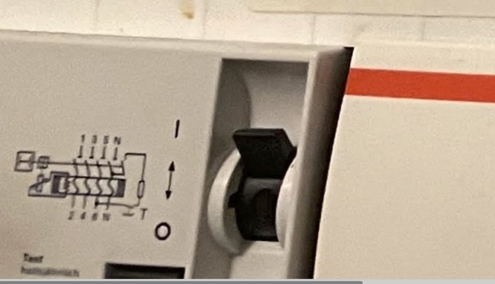 Närbild av en elektrisk huvudströmbrytare i position "på" med schemaillustration.