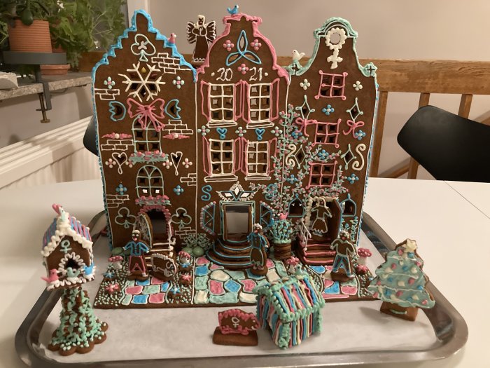 Detaljerat pepparkakshus med färgglada dekorationer på ett bakplåtspapper, utformad för ljusslinga.