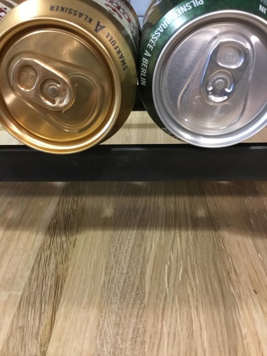 Två ölburkar på ett träbord, en guldig "Arboga" och en grön tysk öl redo för helgens test.