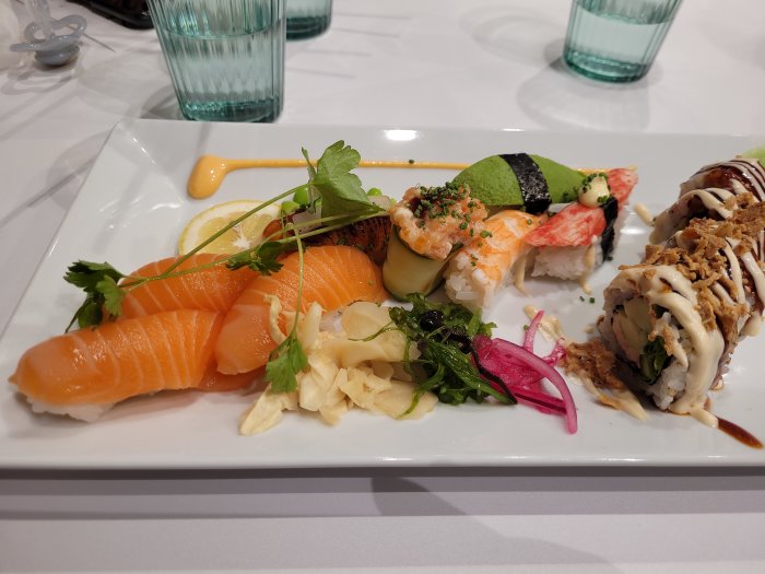 Välupplagd sushi och sashimi tallrik med lax, räkor och olika makirullar.