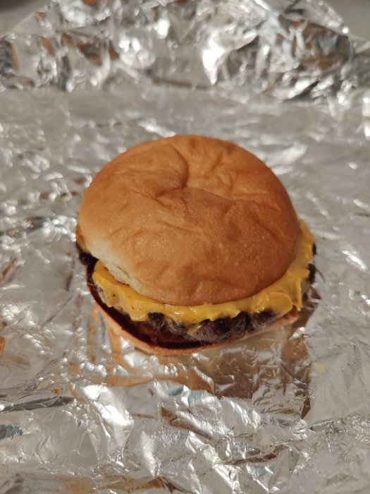 En cheeseburger från Flippin' Burgers förpackad i aluminiumfolie som levererats via Uber Eats.